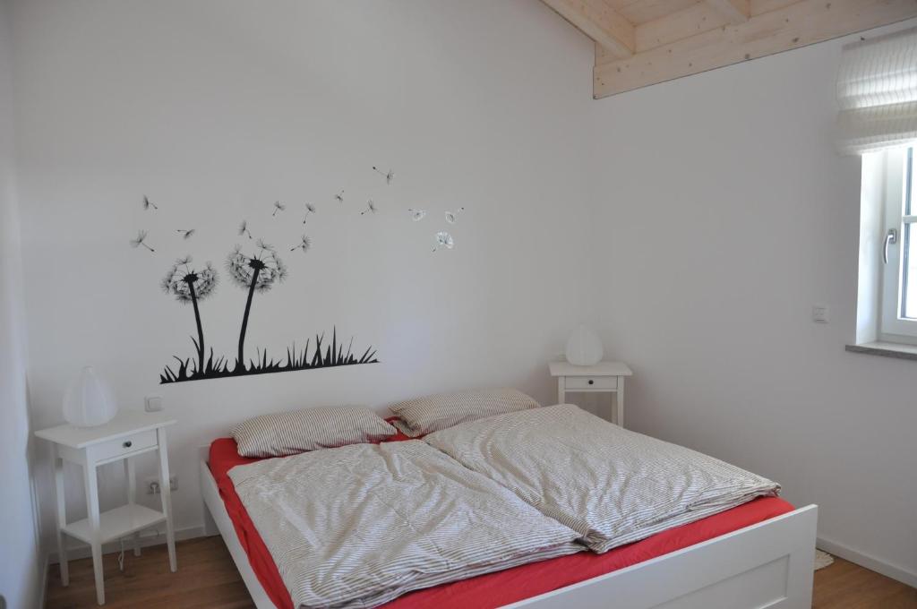 een witte slaapkamer met een bed met paardenbloemen aan de muur bij Ferienwohnungen Rimsting am Chiemsee in Rimsting