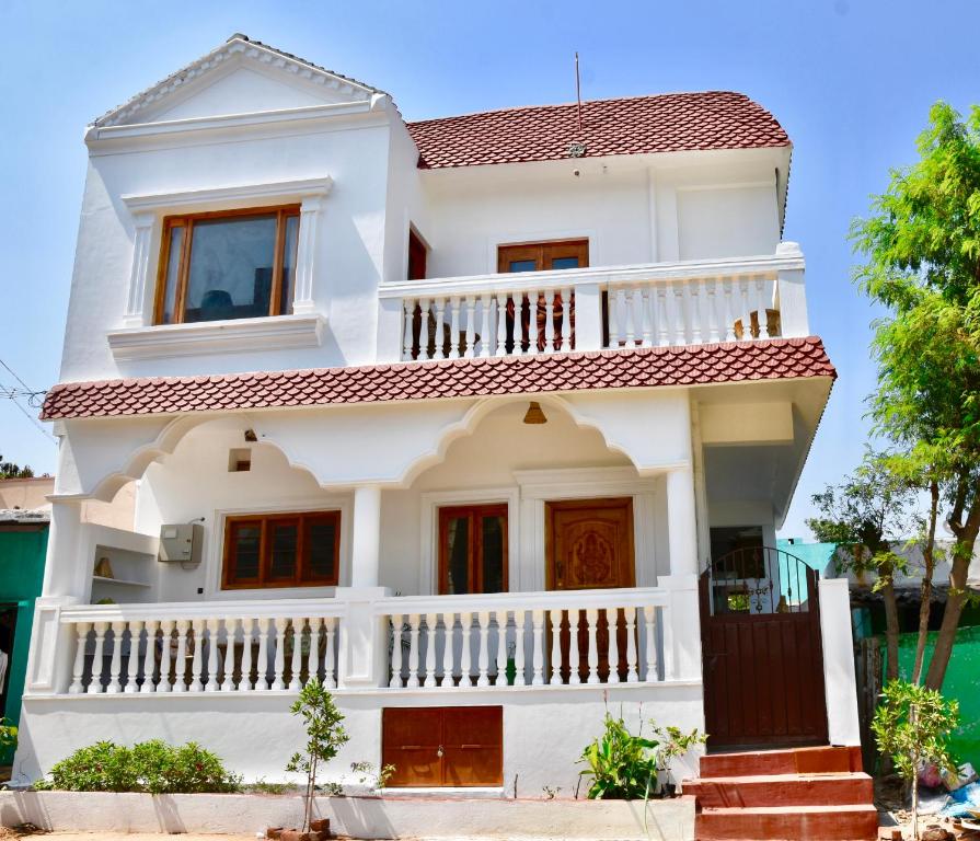 a white house with a red roof at Jasmin Villa in Hampi