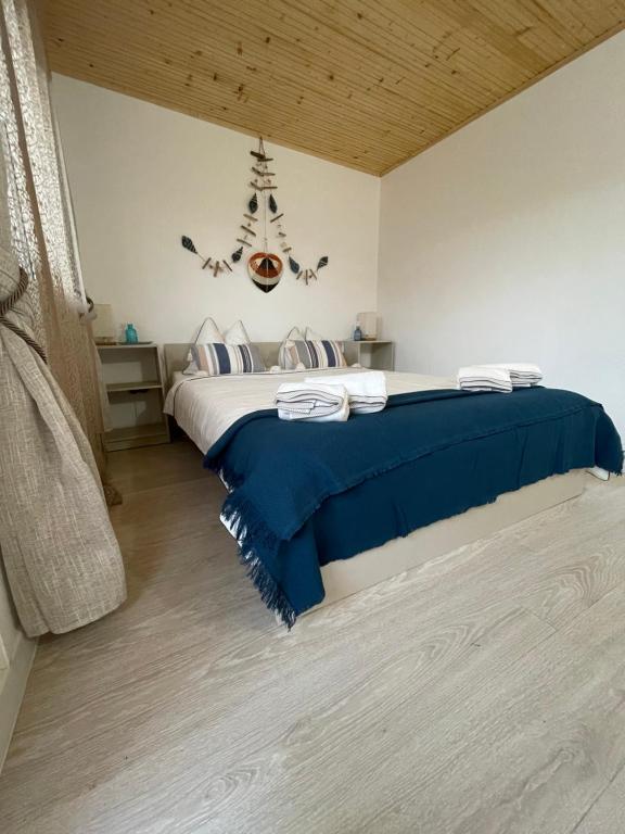 a bedroom with a large bed with a blue blanket at Casuta De La Mare Corbu in Corbu