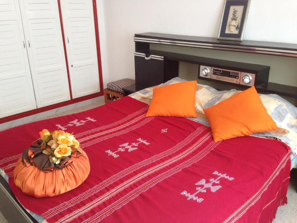 a bed with orange pillows and a pumpkin on it at Appartement Nabeul Plage in Nabeul