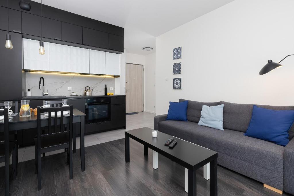 a living room with a couch and a kitchen at Nowa Letnica Apartments by Renters in Gdańsk