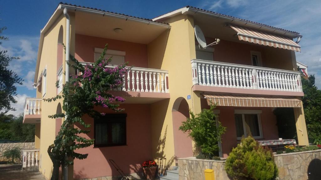 a yellow and pink house with a balcony at Apartmani Stojan in Povljana