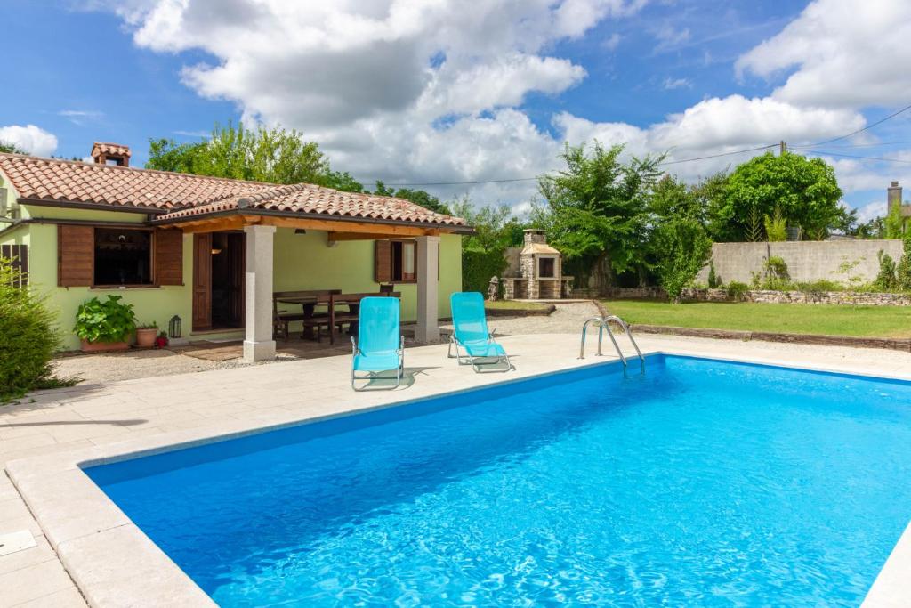 une piscine avec deux chaises bleues et une maison dans l'établissement Villa Chiara with private pool, à Žminj