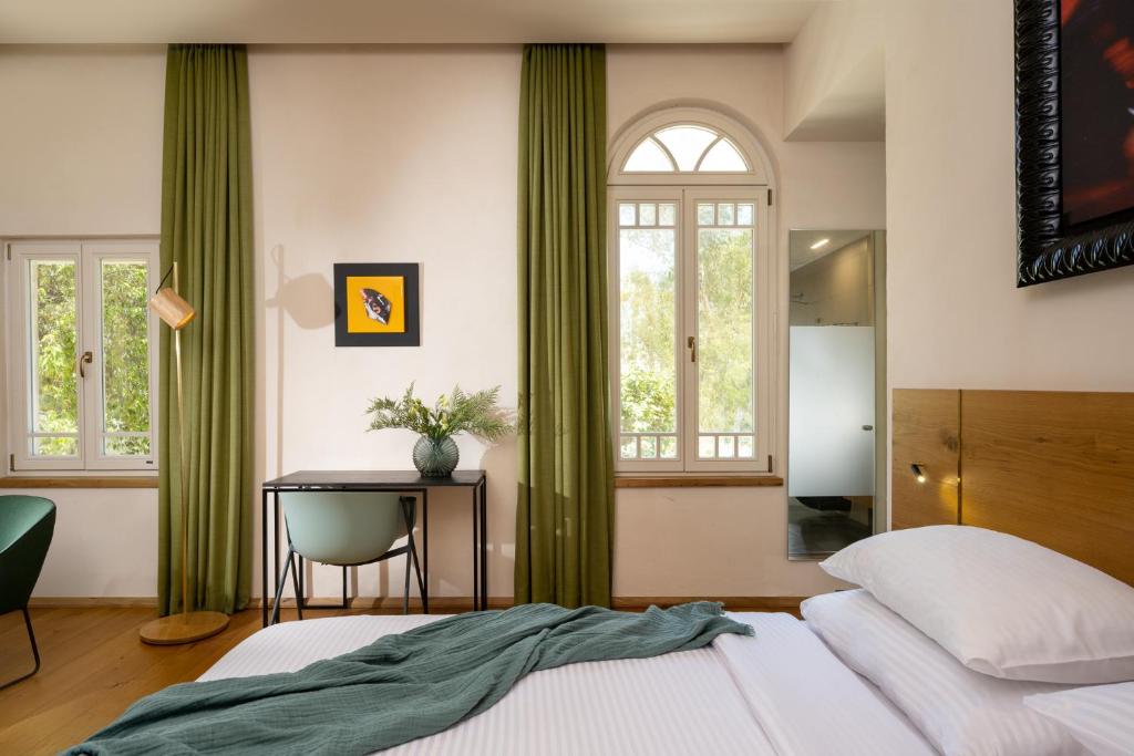 a bedroom with green curtains and a bed and a desk at Schumacher Hotel Haifa in Haifa