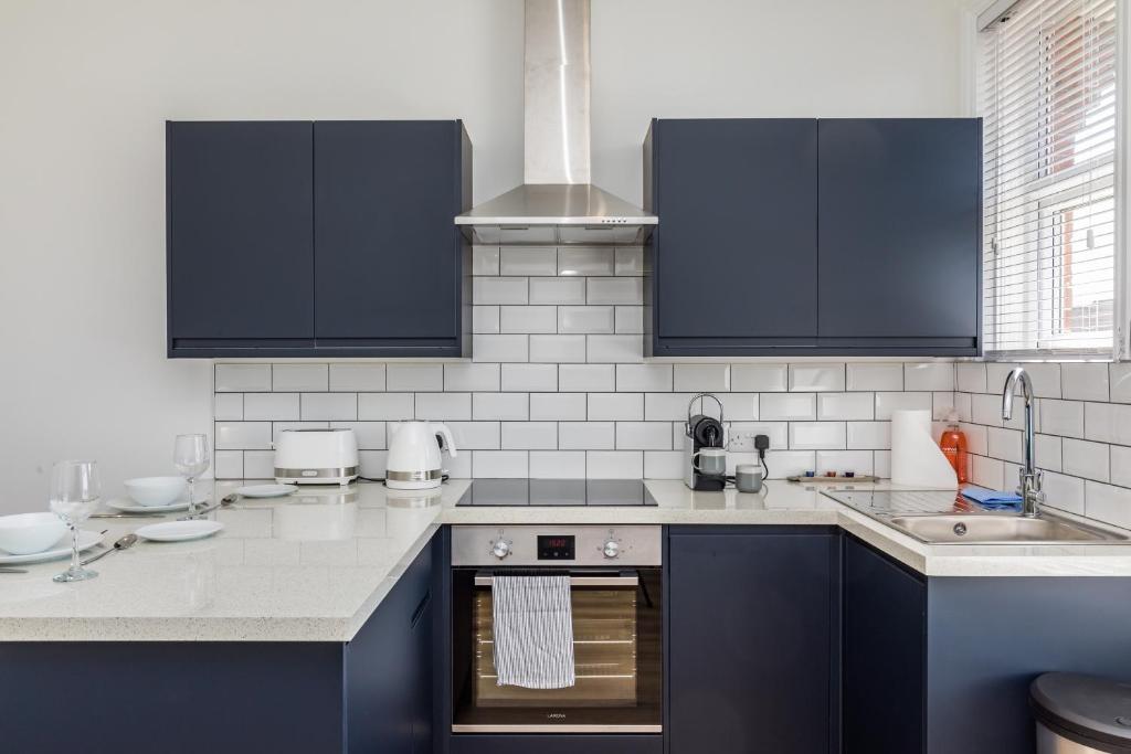 una cocina con armarios azules y fregadero en Hazelgrove Serviced Apartment by Huluki Sussex Stays, en Haywards Heath