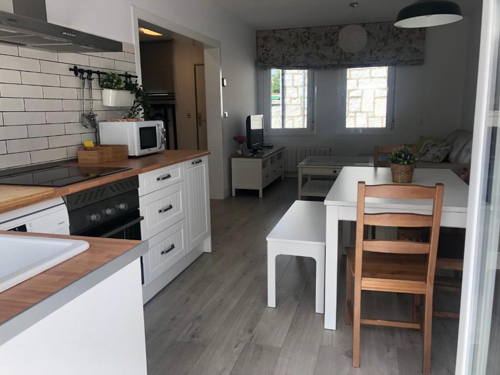 cocina con armarios blancos y mesa con microondas en Casa Navalhorno- barrio nuevo Valsain, en Segovia