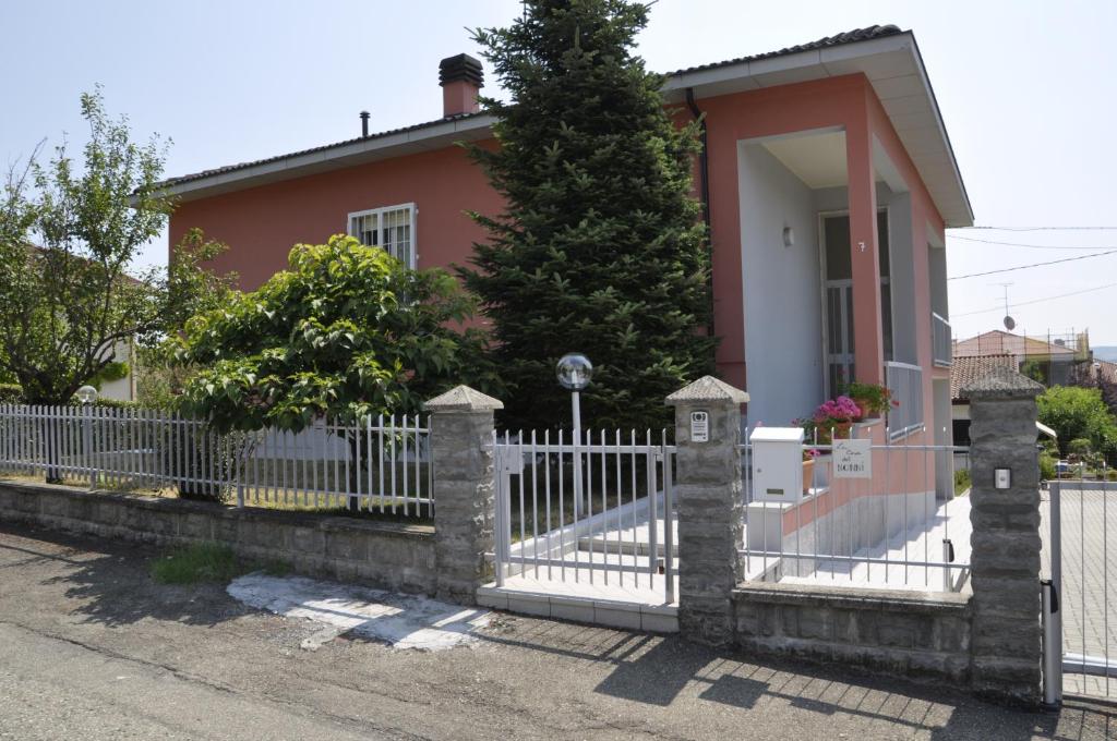 une clôture blanche devant une maison rose dans l'établissement La Casa Dei Nonni, à Felegara