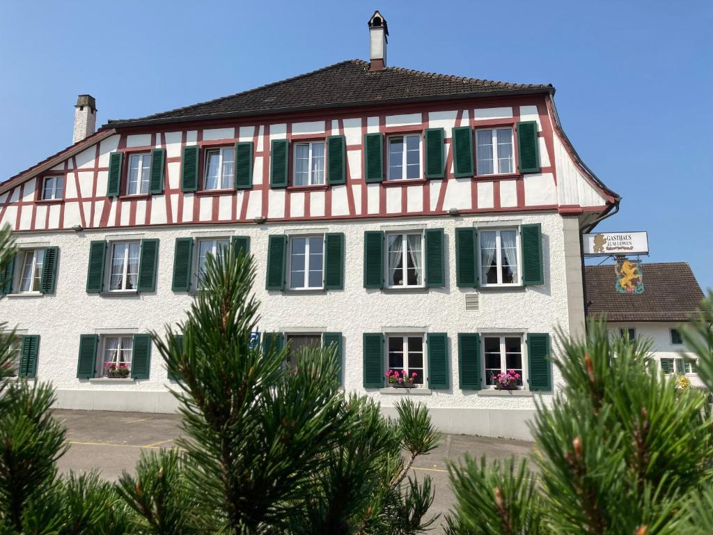 a large white and green building with green shutters at Gasthaus zum Löwen in Neftenbach