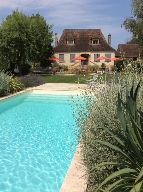 uma piscina azul em frente a uma casa em Autour d'une histoire em Sarlat-la-Canéda