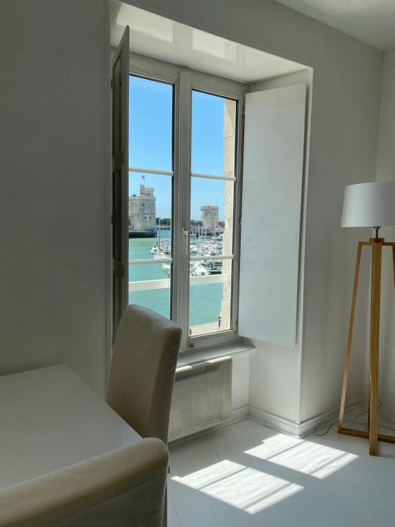 Cette chambre dispose d'une fenêtre avec une table et une chaise. dans l'établissement La Blanche La Rochelle Vue sur les Tours, à La Rochelle