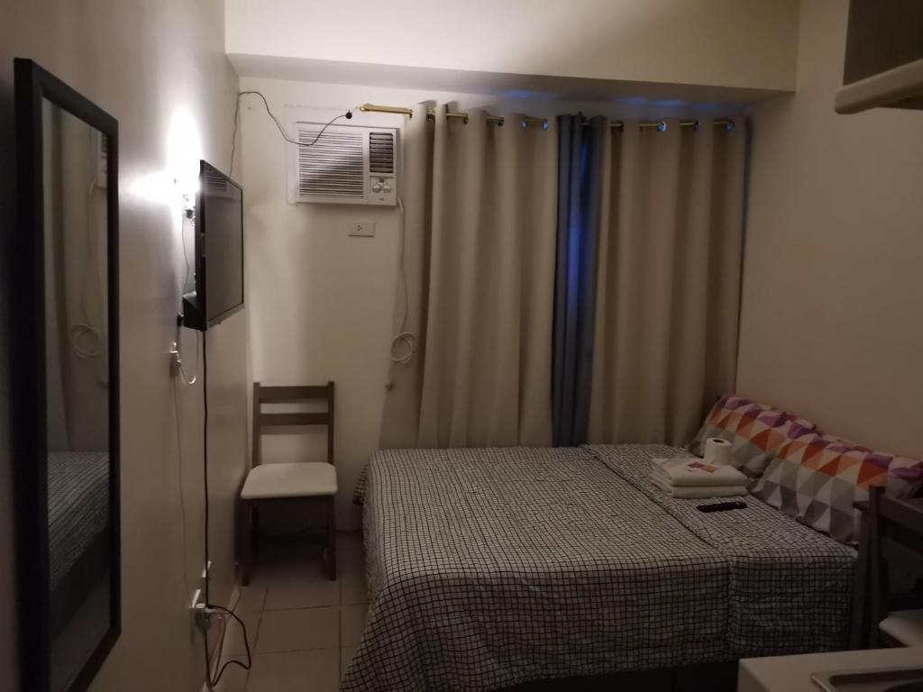 um pequeno quarto com uma cama e uma cadeira em Mack's Awesome Place 24 with Netflix and FastUnliwifi em Manilla
