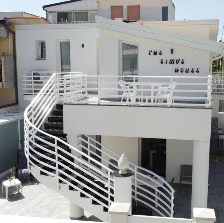 a white house with a white railing on a balcony at The Simo's House Camere a Marzamemi in Marzamemi