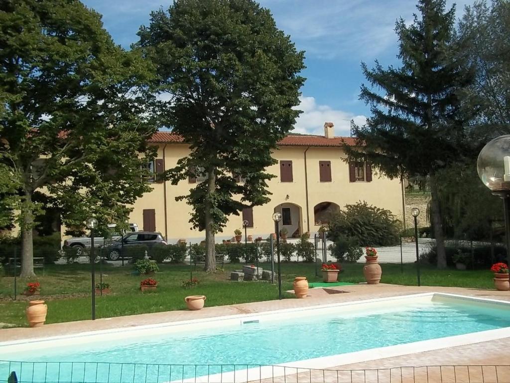 una piscina di fronte a una grande casa di Valle del Poggio a Nocera Umbra