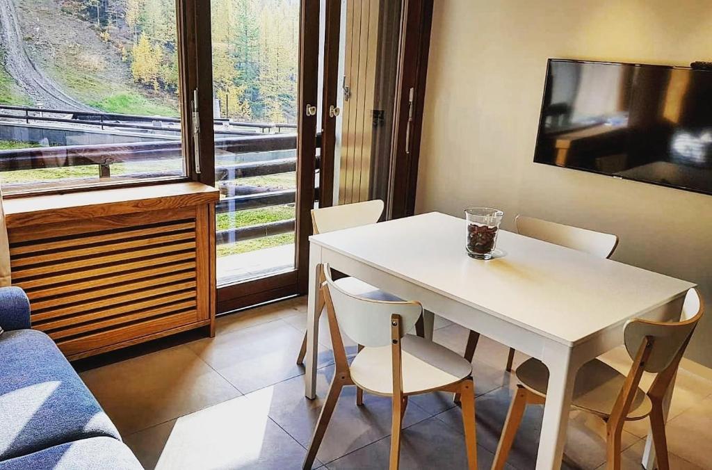 a white table and chairs in a room with a window at Achillea Alpina Cervinia apartment Vda Vacanze in Vetta CIR 0249 in Breuil-Cervinia