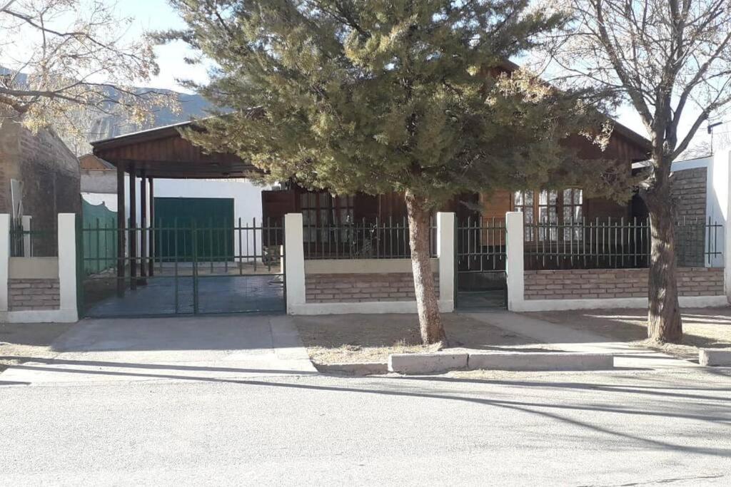 a building with a gate and a tree on a street at Cabaña Uspallata, Mendoza. Para 4 personas in Uspallata