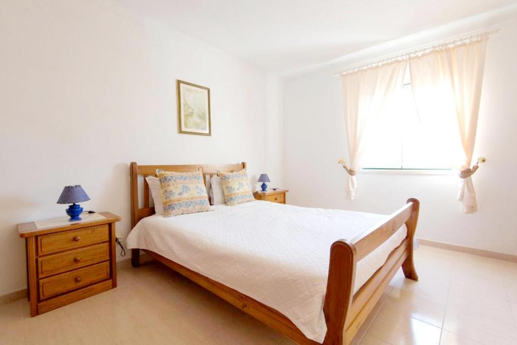a white bedroom with a bed and a window at Villa - Duna Parque Group in Vila Nova de Milfontes
