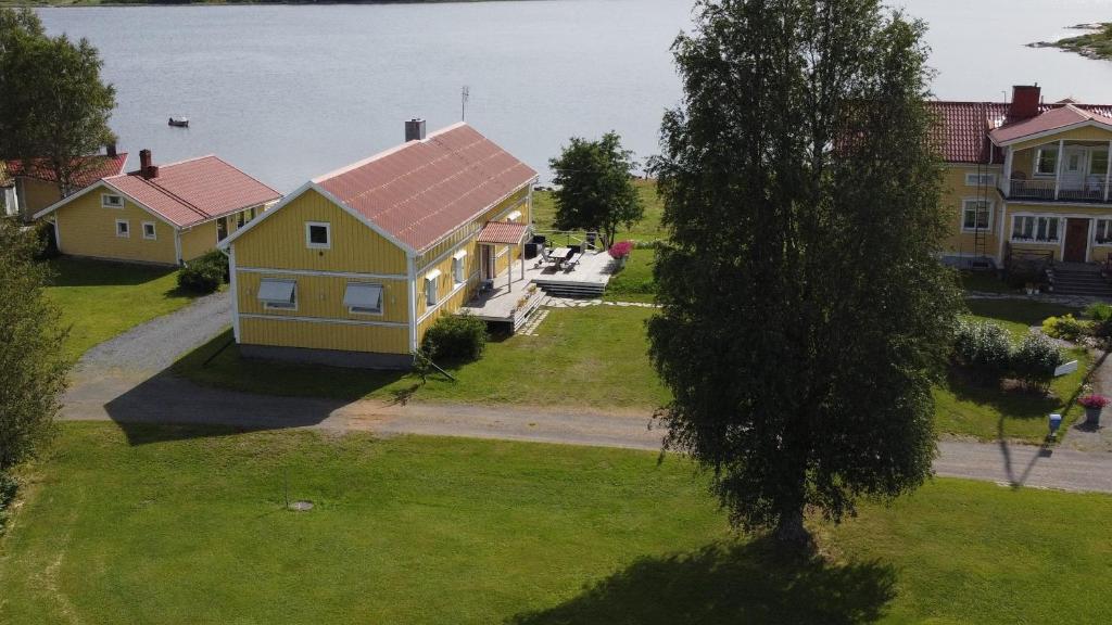 a yellow house with a red roof on a lawn at Nivagården in Korpikylä