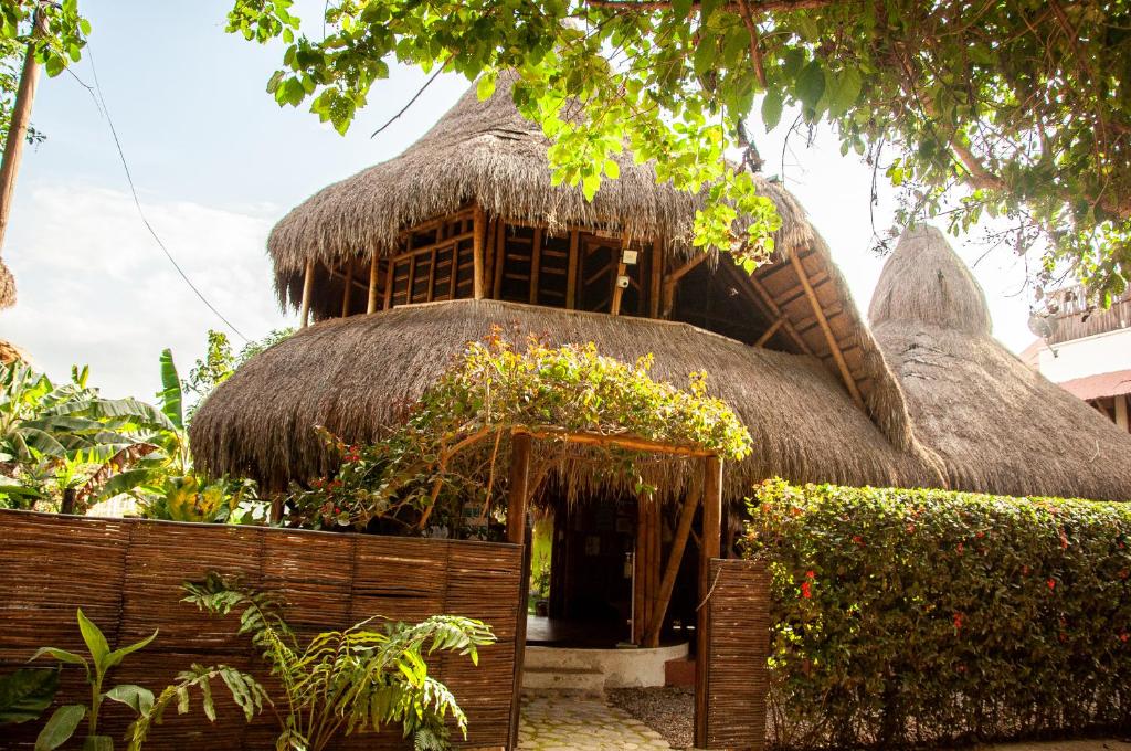 帕洛米諾的住宿－Coco Sänkala Hostel，一座有茅草屋顶的建筑,里面种有植物