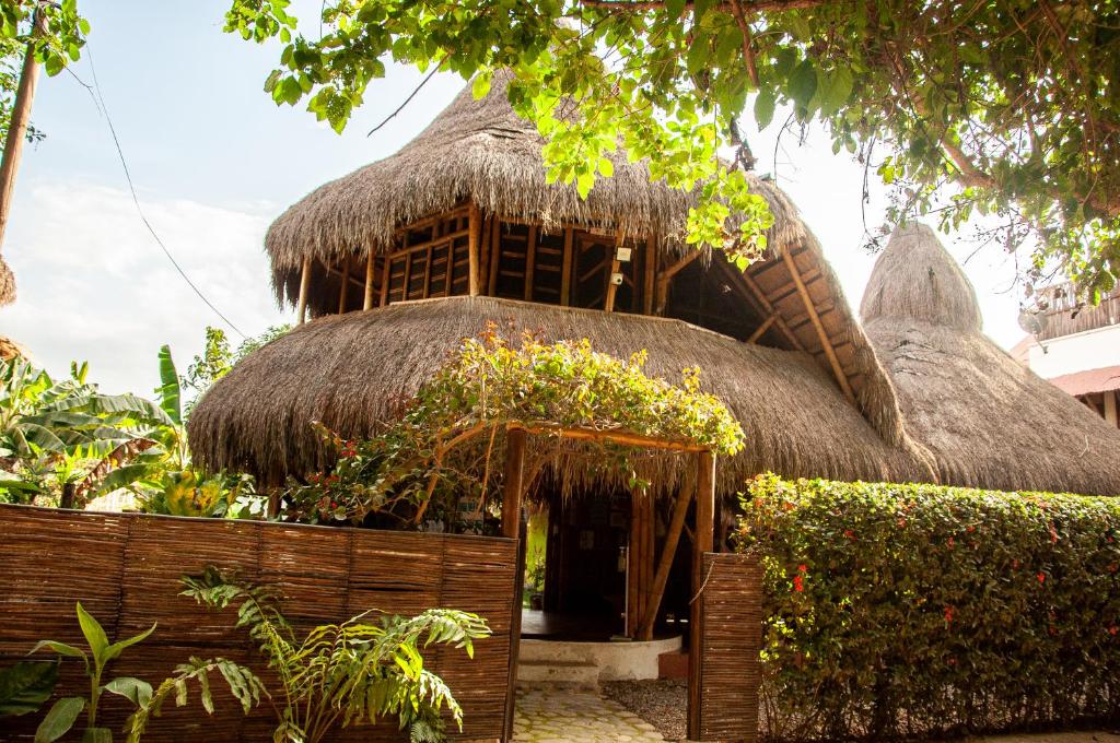 un edificio con techo de paja con plantas. en Coco Sänkala Hostel, en Palomino