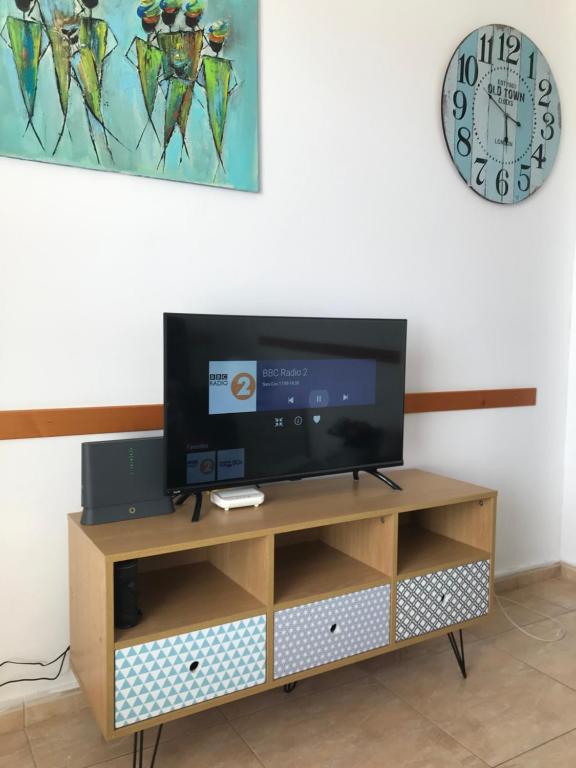 telewizor z płaskim ekranem siedzący na szczycie drewnianego centrum rozrywki w obiekcie Yumbo Beach Apartment 2 with high speed free internet w mieście San Bartolomé