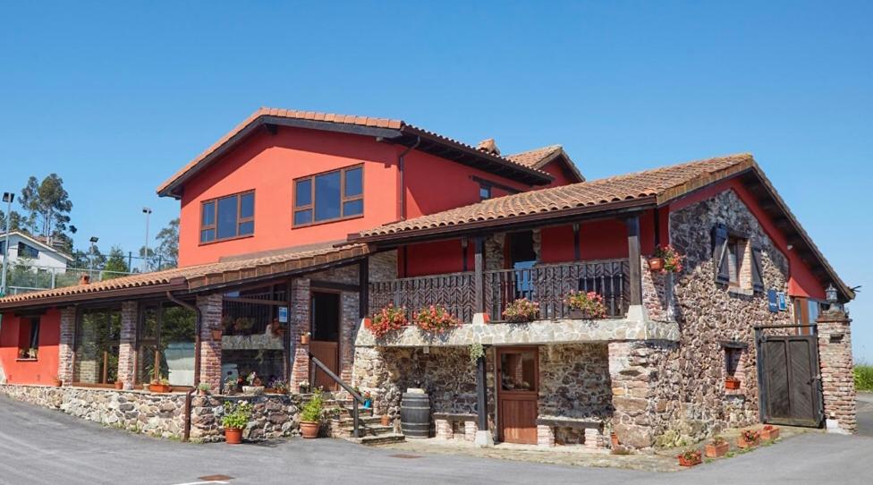 a large red building with flowers in front of it at Hotel Tejera del Nalon in Soto del Barco