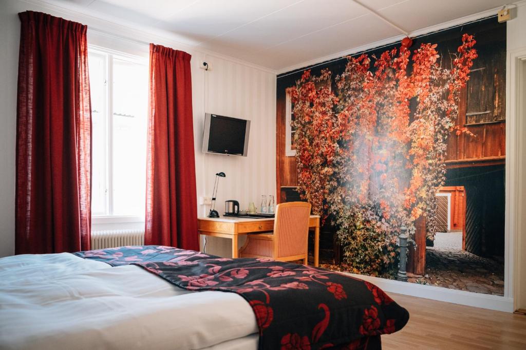 a bedroom with a bed and a desk and a painting at Eksjö Stadshotell Annex in Eksjö