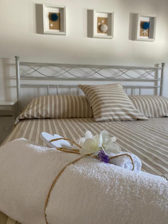 Una cama con una toalla blanca con una flor. en Pinulà, en Maruggio