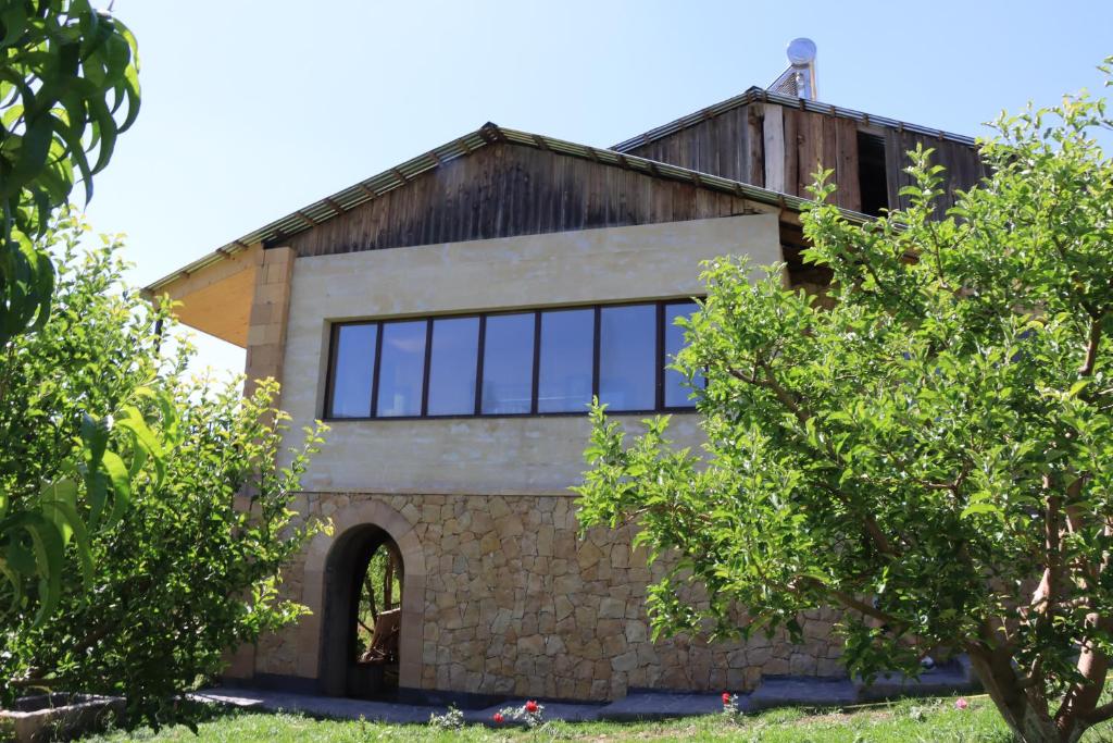 ein Haus mit Glasfenstern und einer Steinmauer in der Unterkunft Gnishik Eco Resort in Gnishik