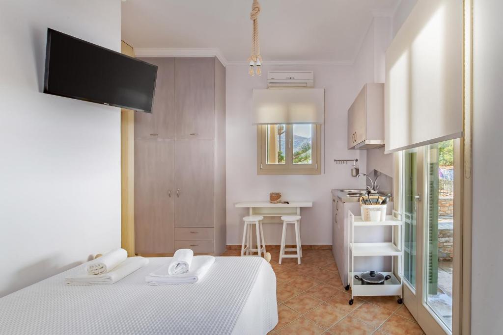 Habitación blanca con cama y cocina en Nysa Residence en Ándros