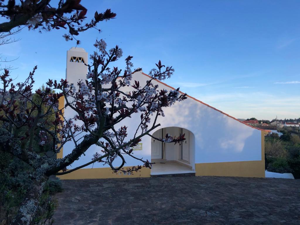 un bâtiment blanc et jaune avec une tour d'horloge dans l'établissement Quinta dos Girassóis FZ, à Ferreira do Zêzere