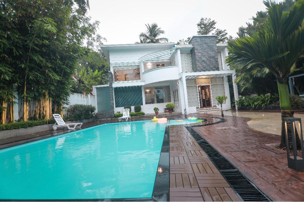 a villa with a swimming pool in front of a house at Square Villa Residency Luxury 1 Bed Room Villa with Private Pool in Mukkam