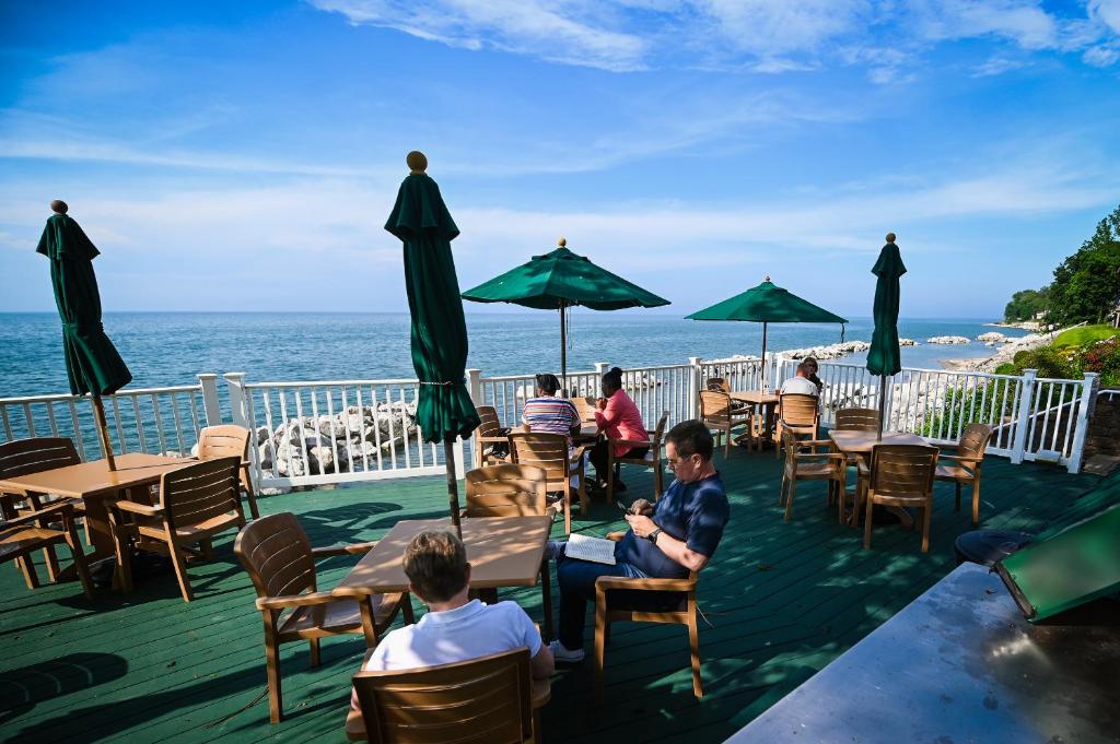 a group of people sitting at tables on a deck near the ocean at The Lakehouse Inn Geneva in Geneva-on-the-Lake
