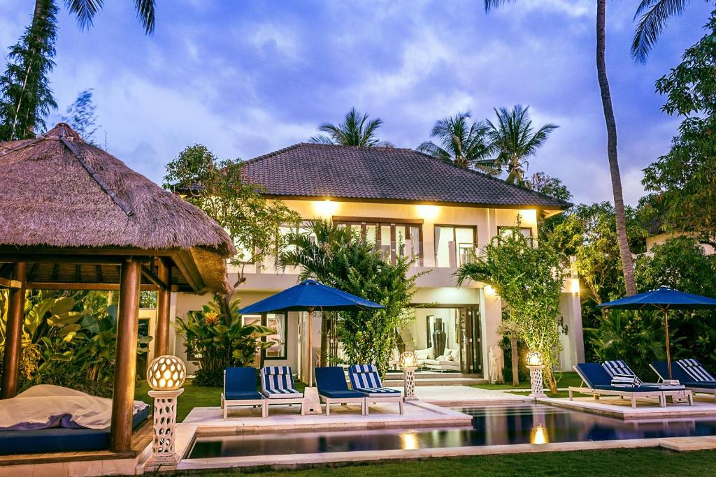 une villa avec une piscine et des chaises bleues dans l'établissement The Beach Front Villas - North Bali, à Kubutambahan