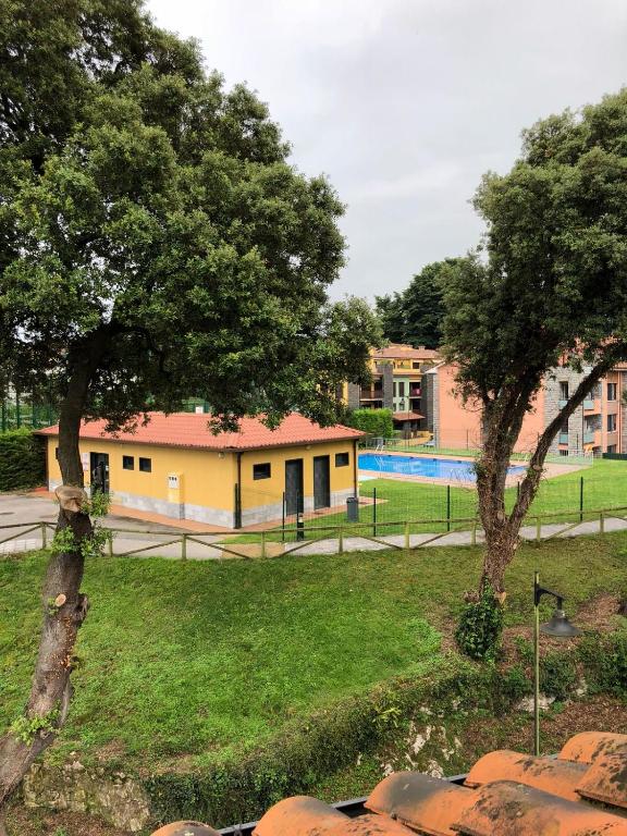 two trees in a park with a building and a pool at MARINA LLANES IV in Llanes