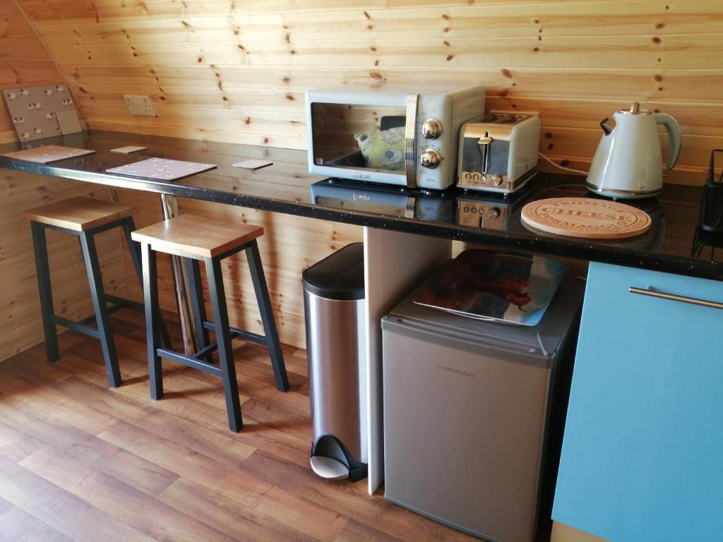 a kitchen with a counter with a microwave and stools at Portnalong Pod in Port na Long