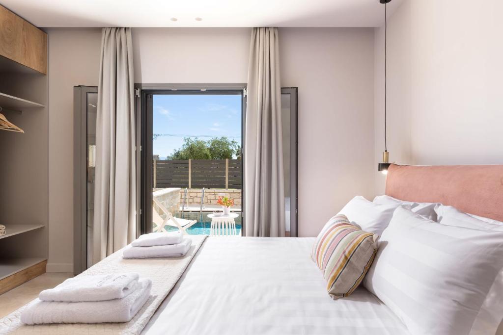 um quarto com uma grande cama branca com toalhas em Onore Luxury Suites em Kato Korakiana
