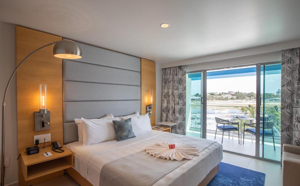a hotel room with a large bed and a balcony at The Morgan Resort Spa & Village in Simpson Bay