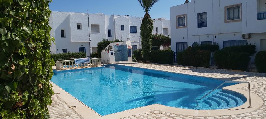 a swimming pool in front of a building at Très beau studio avec piscine in Hammamet Sud