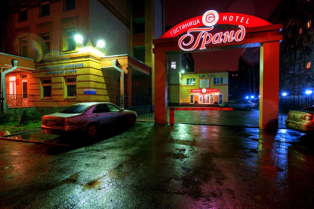 a car parked in a parking lot with a neon sign at Grand Hotel in Tambov