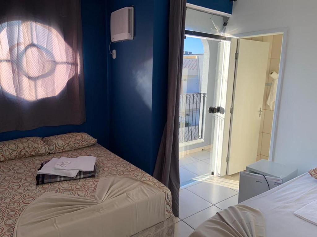 a bedroom with a bed and a door to a balcony at Hotel Mão de Fatima in Aparecida