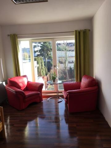 uma sala de estar com duas cadeiras vermelhas e uma janela em Willa Tanagra em Poznań