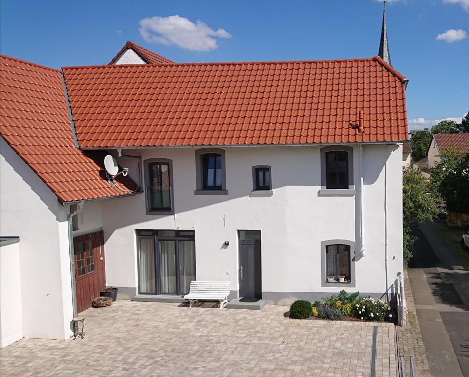 a white house with an orange roof at Ferienhaus Anno 1903 in Weisenheim am Berg