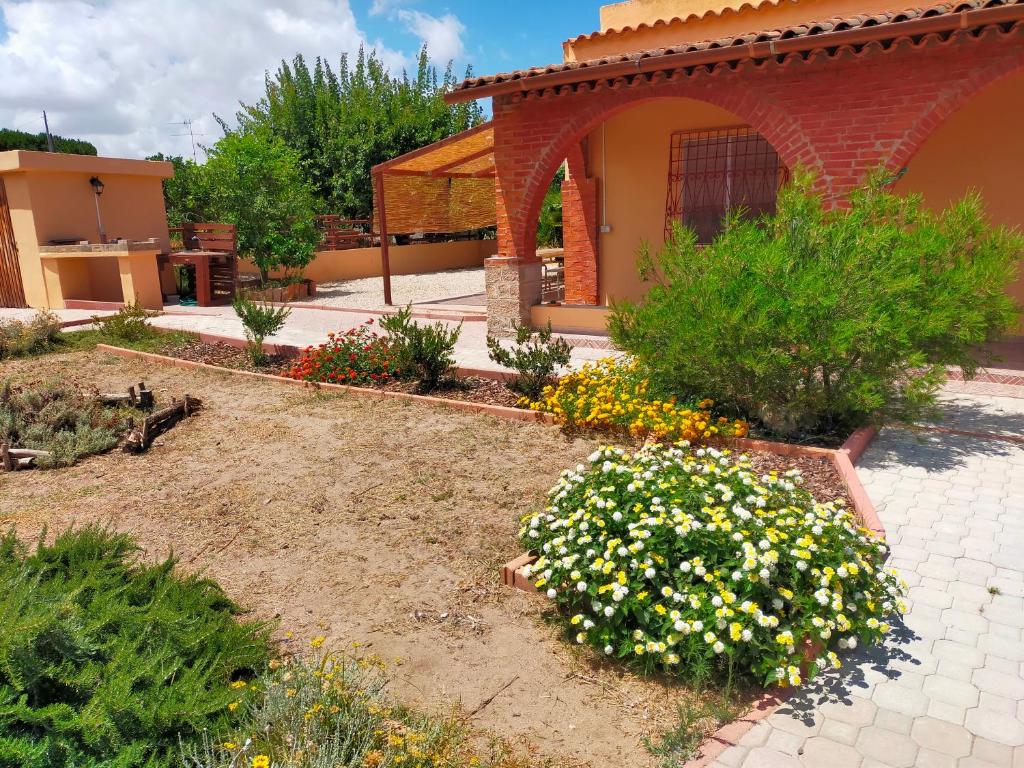 a garden with flowers in front of a house at Casa Marina Lu Tuvaraggiu Casa vacanze in Sorso