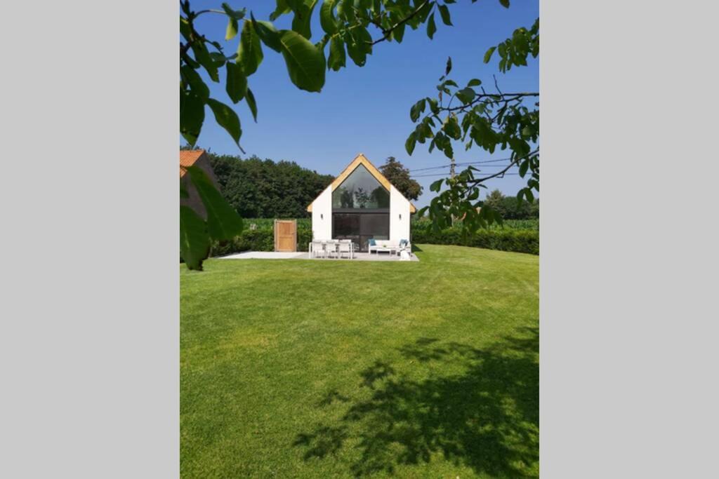 un pequeño edificio blanco en un campo de césped en Vakantiewoning Hélence, en Merendree