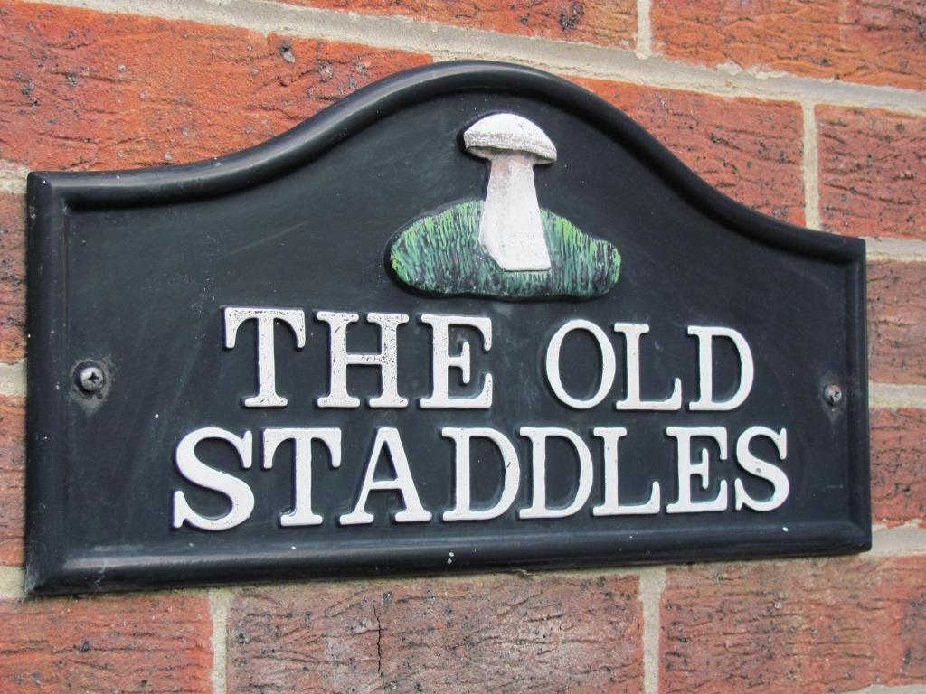 a sign on the side of a brick wall with an old stalker at The Old Staddles Annex in Ludgershall