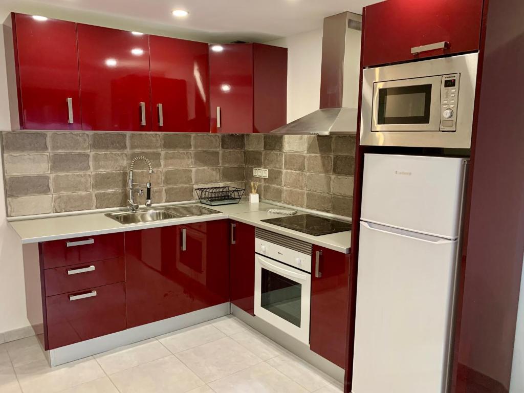 a kitchen with red cabinets and a sink at La dama gris - Fuerteventura Holiday Wi-Fi in Costa de Antigua