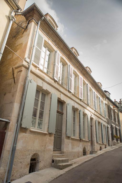 an old building with white shutters on a street at La Maison du Haut in Tonnerre
