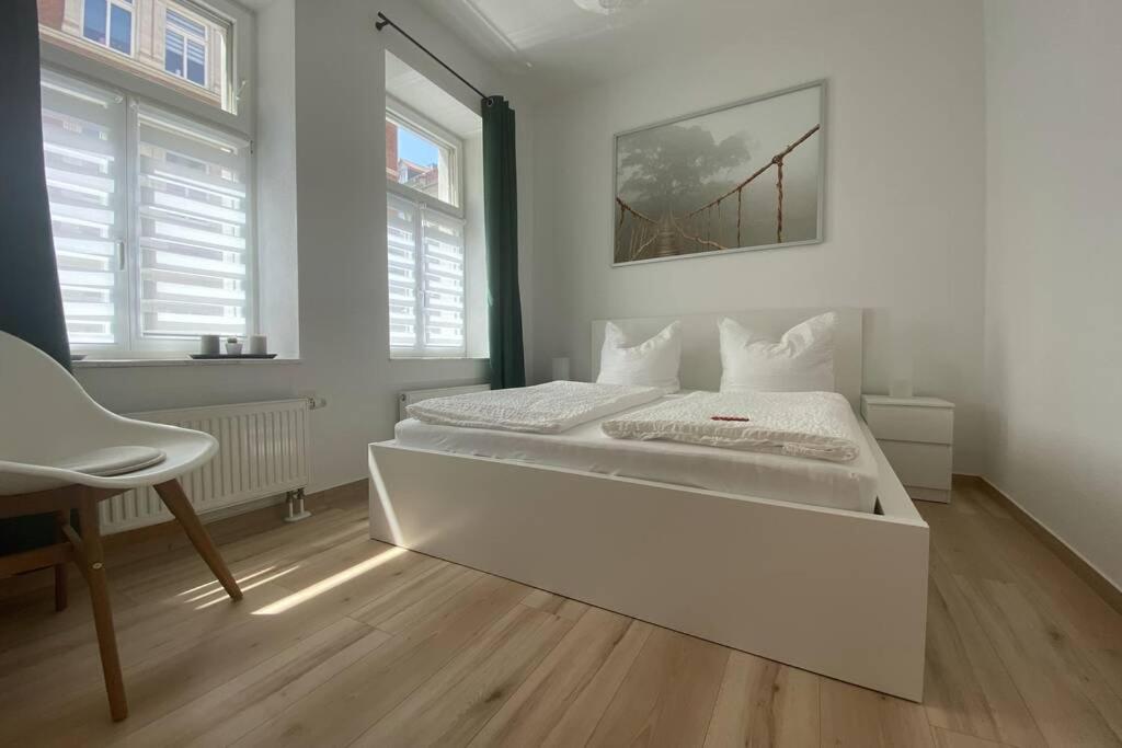 a white bedroom with a large bed and a desk at Gemütliche Ferienwohnung in zentraler Lage in Erfurt