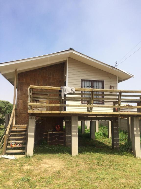 a house with a large deck in front of it at CASA EN PALAFITO in El Quisco