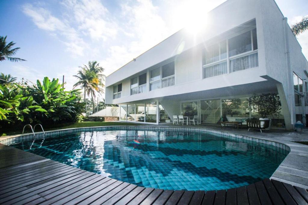 a house with a swimming pool in front of a building at Guest House Guarujá Hotel Boutique in Guarujá